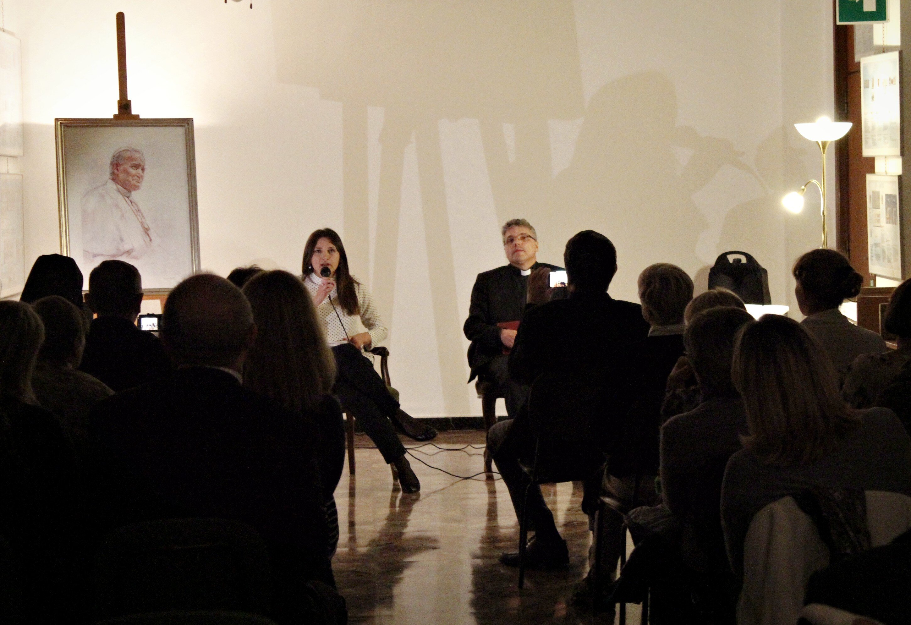 An event with an audience, with a portrait of St John Paul II in the background
